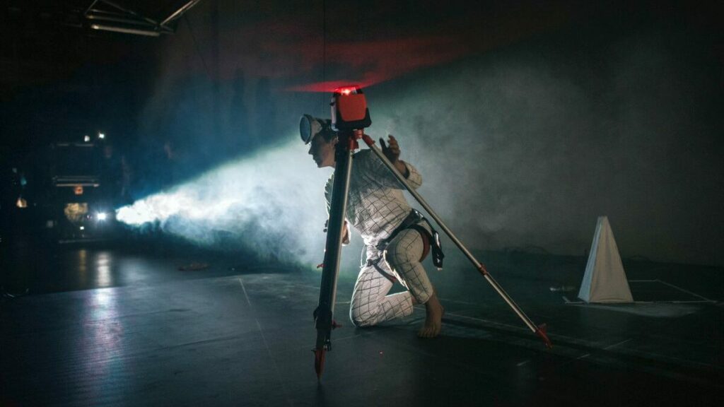 a person with a building laser, in the background some light, smoke, a pyramid
